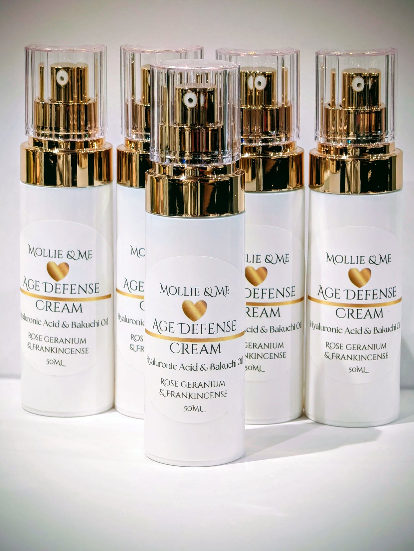 Four bottles of Mollie & Me Age Defense Cream on a white background