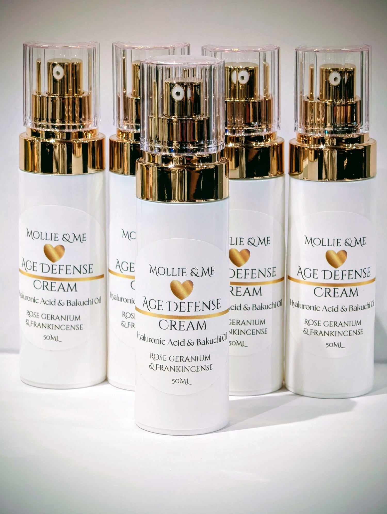 Four bottles of Mollie & Me Age Defense Cream on a white background