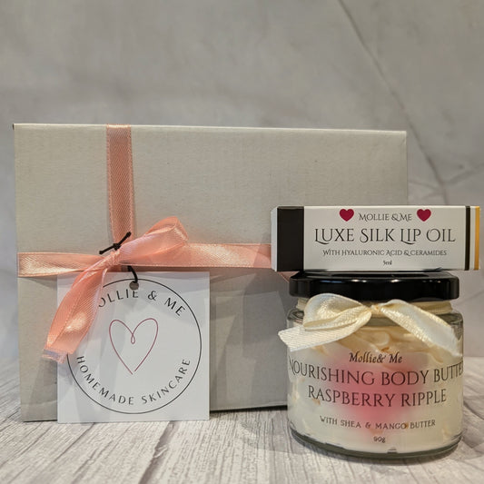 A Mollie & Me skincare pamper box featuring a 90g Shea body butter and a luxe Silk Natural lip oil in a white gift box with a pink ribbon and label.
Small batch skincare made in Kent.
